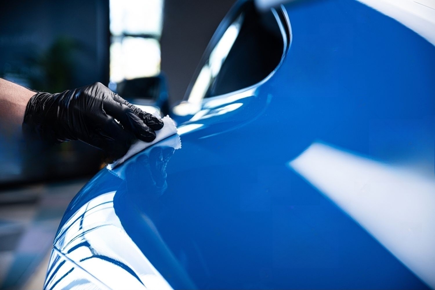 Ceramic coating and paint correction package by Peak Polish Mobile Detailing: a technician applying ceramic coating to a blue car for enhanced protection and shine.